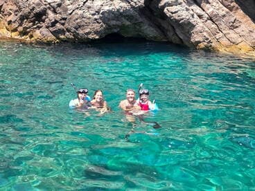A joyful family enjoys snorkeling in crystal-clear waters, surrounded by stunning rock formations — a perfect adventure for creating unforgettable memories.