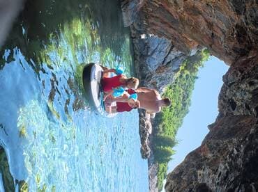 A family enjoys paddleboarding in a serene cove, surrounded by stunning rock formations and clear waters — a perfect adventure for creating lasting memories.