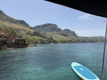 A stunning view of a tranquil coastline with clear turquoise waters and a paddleboard in the foreground, perfect for exploring the beautiful landscapes of the area.