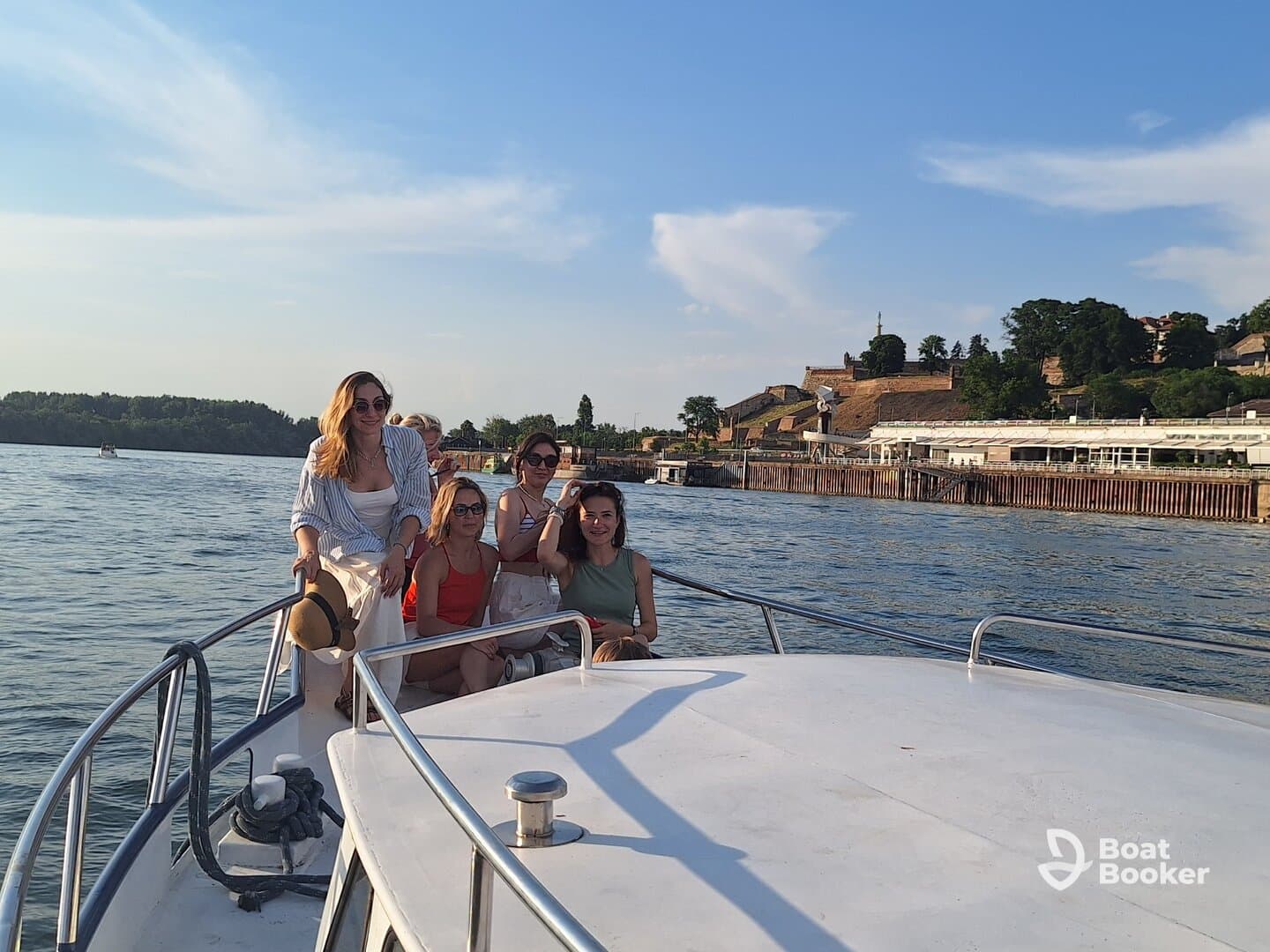 A group of friends enjoys a sunny day on a boat, capturing joyful moments together against a scenic backdrop — perfect for celebrations and outings on the water.