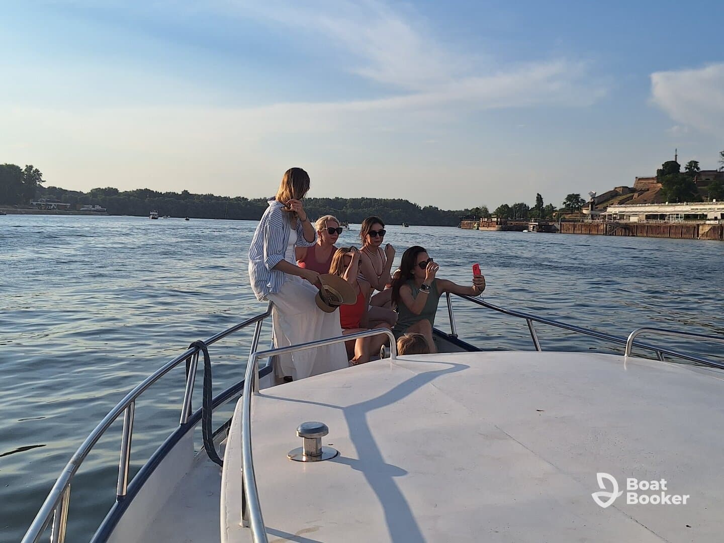 A group of friends enjoys a fun moment on a boat, taking selfies and celebrating under the warm glow of the sunset — perfect for memorable outings on the water.