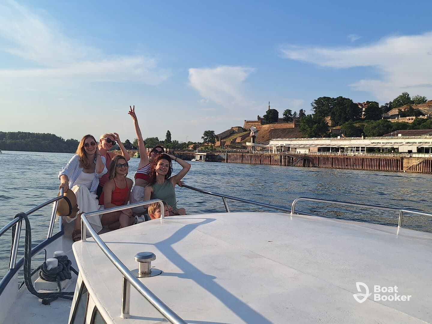 A joyful group of friends enjoys a boat ride, celebrating together with smiles and laughter against a scenic backdrop — perfect for memorable outings on the water.