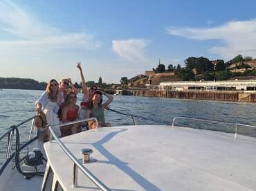 A joyful group of friends enjoys a boat ride, celebrating together with smiles and laughter against a scenic backdrop — perfect for memorable outings on the water.