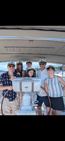 A joyful group of friends and family, including a child, gather on a boat, showcasing their excitement and camaraderie while enjoying a day on the water.