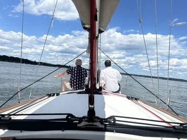 Two friends enjoy a sailing experience on a calm day, surrounded by beautiful clouds and water — perfect for a relaxing day on the boat.