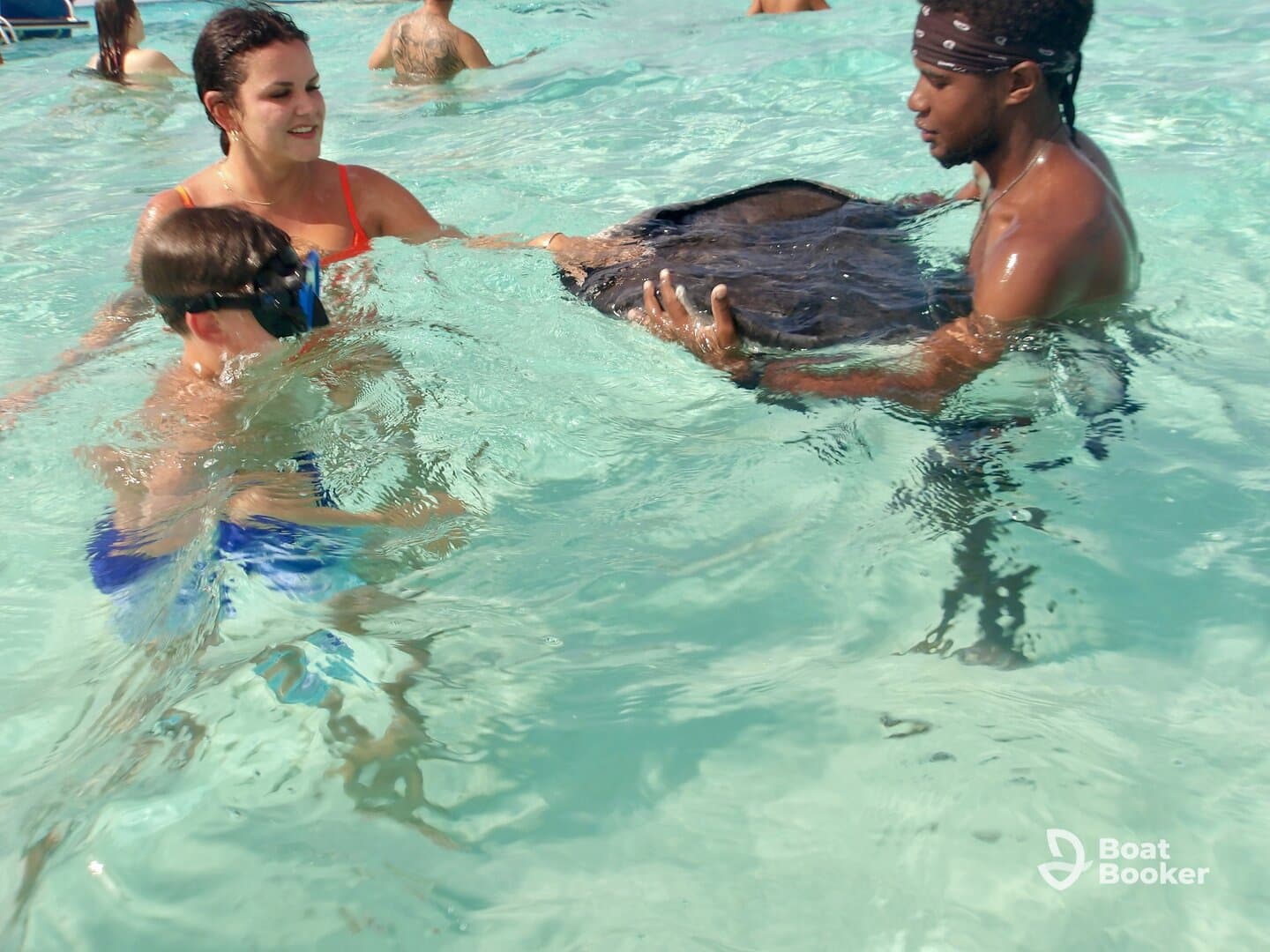 A child and an adult interact with a stingray in shallow waters, showcasing a memorable wildlife experience in a tropical setting.