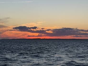 A stunning sunset over the water, showcasing vibrant colors against the horizon — an ideal backdrop for evening boat cruises.