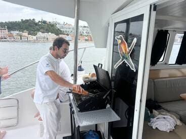 A chef prepares food on a grill aboard a yacht, showcasing onboard amenities for a delightful dining experience at sea.
