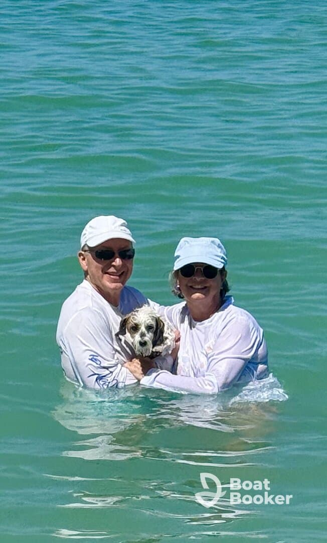 A happy couple enjoys a refreshing swim with their dog in the clear waters, capturing a joyful moment perfect for beach outings and family adventures.