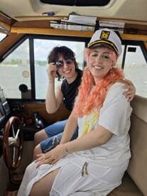 Two friends enjoy a moment inside the helm of a boat, showcasing a cozy cabin atmosphere perfect for navigating the waters.