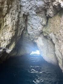 A stunning view from inside a cave, showcasing the shimmering water and light at the entrance — a perfect spot for exploring hidden gems while boating.