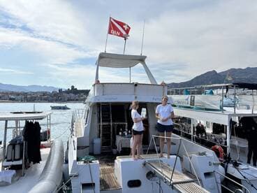 Two crew members stand on the deck of a diving boat, ready for an adventure on the water — perfect for diving enthusiasts exploring the beautiful coastline.