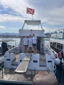 A group of three individuals poses on the deck of a boat named 'Futura,' showcasing a perfect moment for celebrations or group outings on the water.