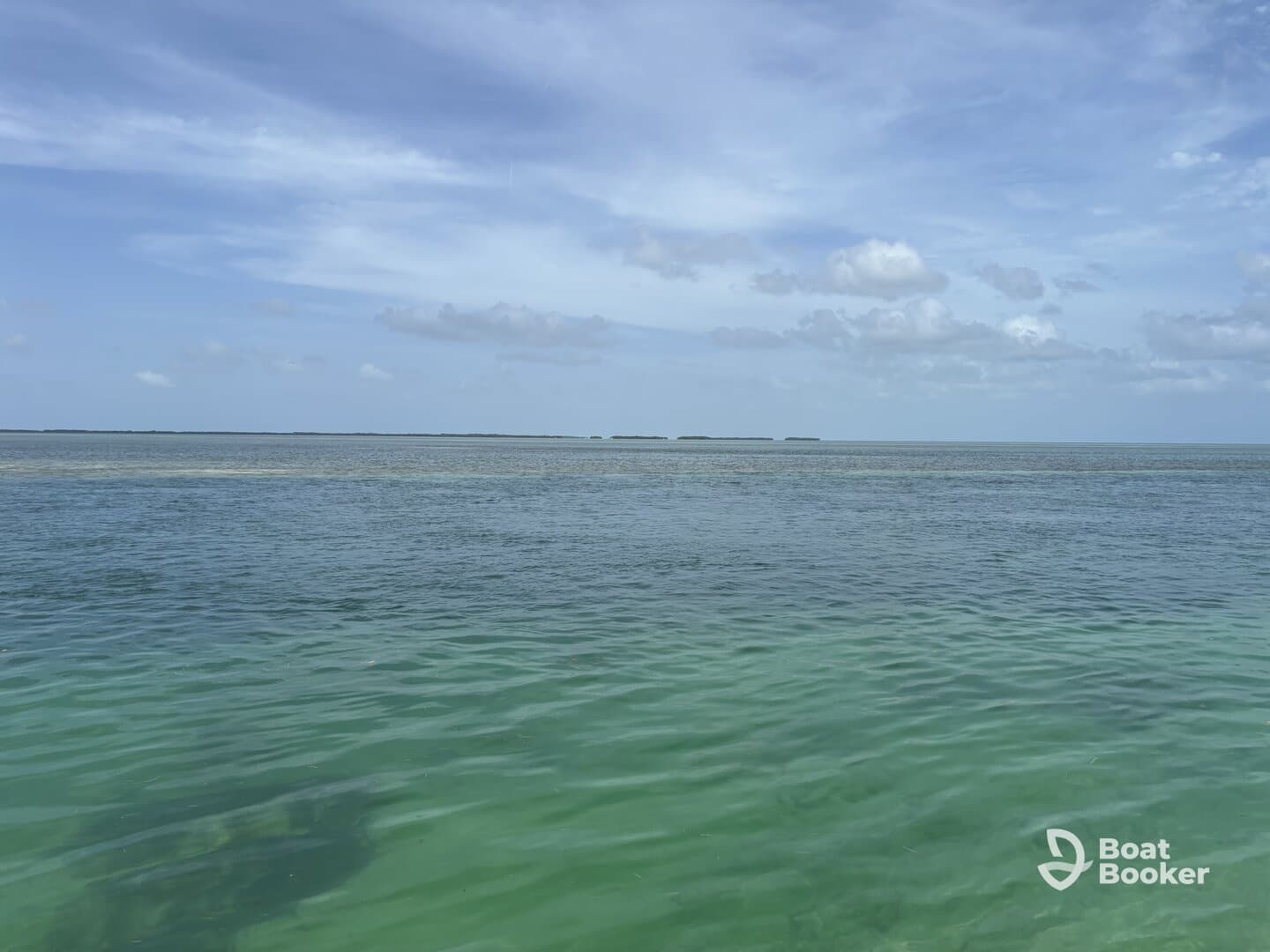 A scenic view of calm waters under a partly cloudy sky, showcasing the tranquility of the ocean landscape.