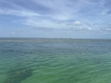 A scenic view of calm waters under a partly cloudy sky, showcasing the tranquility of the ocean landscape.