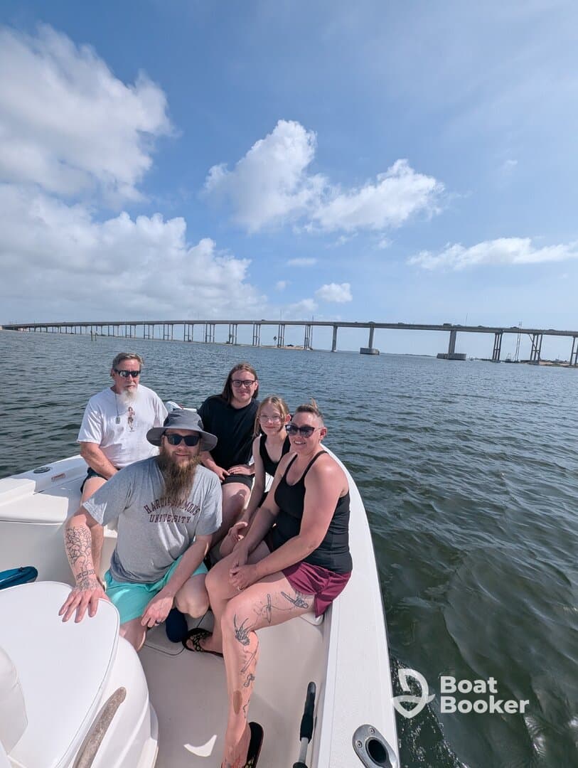 A cheerful group of friends enjoys a day on the water, capturing the essence of fun and relaxation aboard their boat with a scenic bridge in the background.