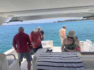A group of friends enjoys a sunny day on the boat, with drinks in hand and the beautiful ocean as their backdrop — perfect for a relaxing getaway.
