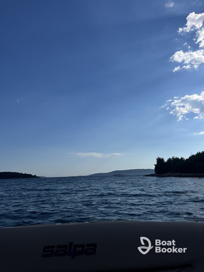 A serene view of the water and distant islands from the deck of a Salpa boat, showcasing the beauty of a day on the water.