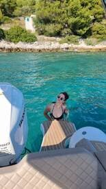 A woman enjoys a refreshing swim next to a boat in crystal-clear waters, perfect for summer adventures and relaxation on the water.