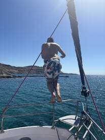 A person prepares to jump off the side of a boat into the sparkling ocean, capturing the thrill of summer adventures on the water.