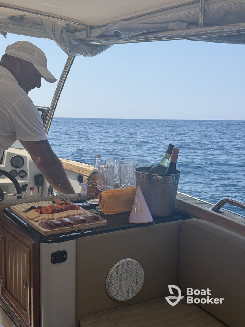 A crew member prepares a festive spread of food and drinks aboard a boat, perfect for celebrations on the water.
