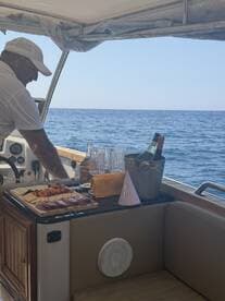A crew member prepares a festive spread of food and drinks aboard a boat, perfect for celebrations on the water.