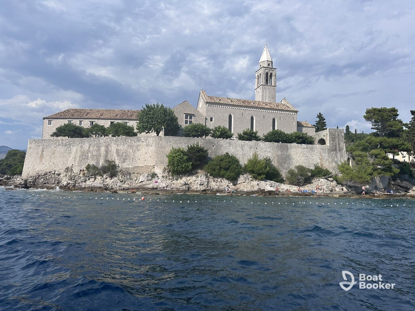 A picturesque view of a historic building along the coastline, with people enjoying the beach nearby — a perfect representation of scenic coastal destinations.