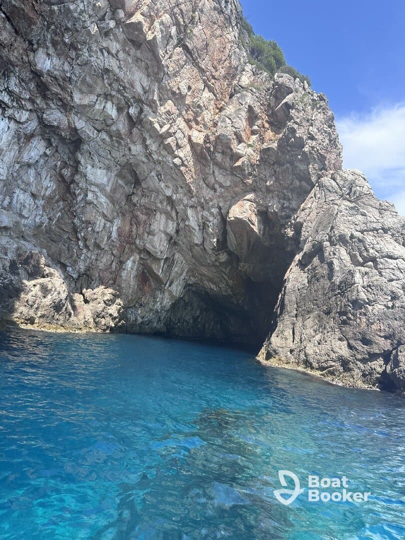 A stunning view of a rocky coastline with a cave entrance, surrounded by crystal-clear blue waters — a perfect destination for exploration and adventure.