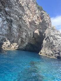 A stunning view of a rocky coastline with a cave entrance, surrounded by crystal-clear blue waters — a perfect destination for exploration and adventure.