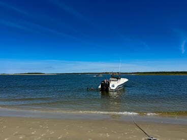 A boat is anchored near the beach with a person swimming nearby, showcasing a perfect day on the water.