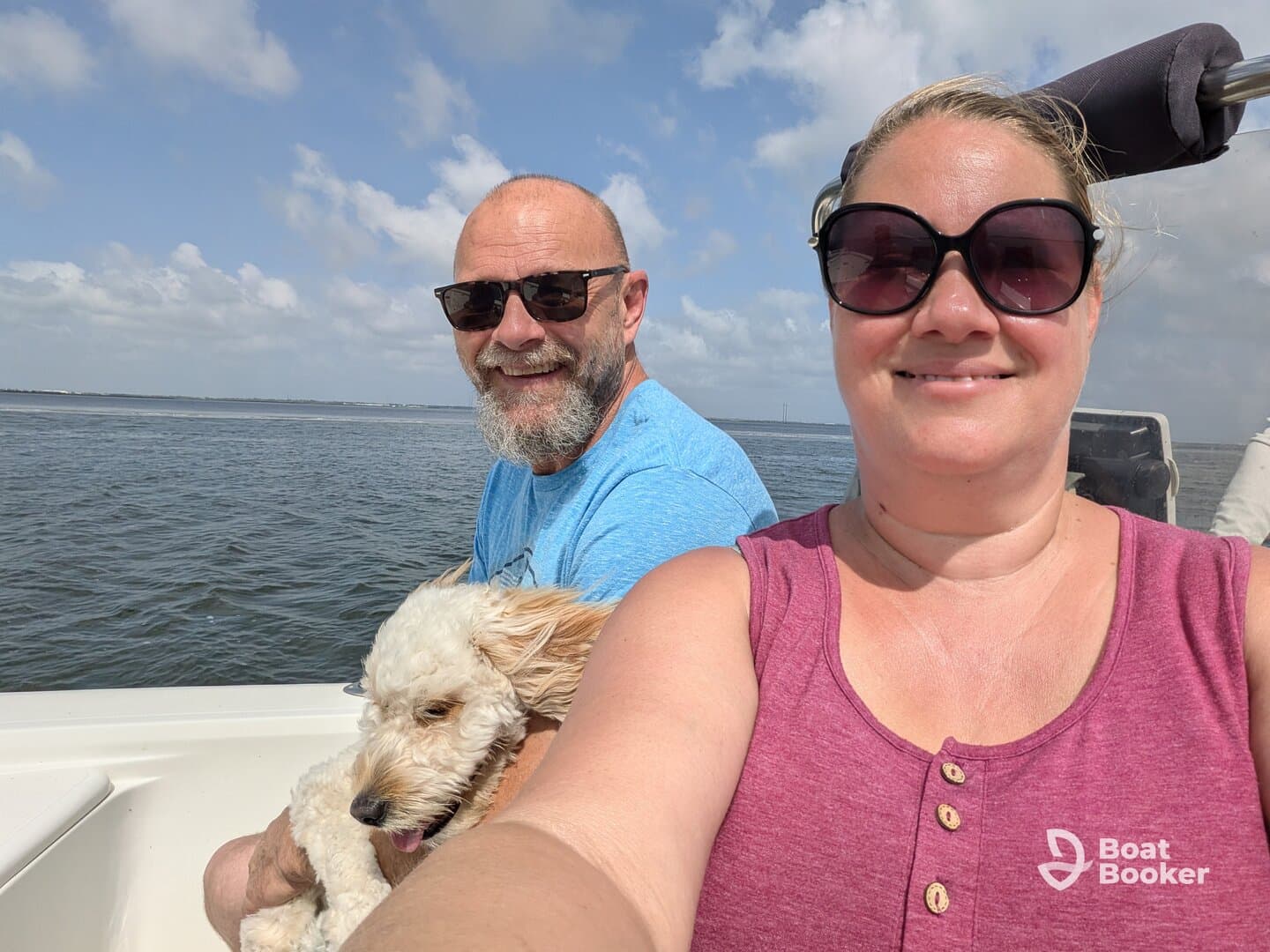 A cheerful couple enjoys a day on the water with their dog, capturing a perfect moment of joy and adventure while boating.