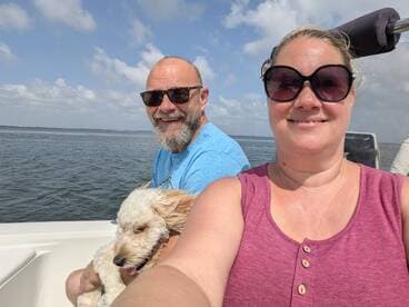 A cheerful couple enjoys a day on the water with their dog, capturing a perfect moment of joy and adventure while boating.