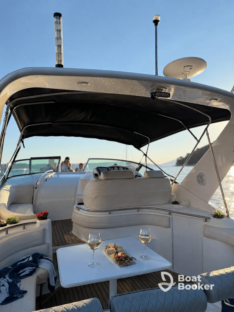 An inviting interior view of a boat's cabin featuring comfortable seating and a dining area with wine and snacks, perfect for relaxing outings on the water.