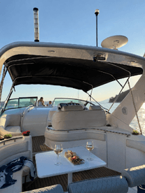 An inviting interior view of a boat's cabin featuring comfortable seating and a dining area with wine and snacks, perfect for relaxing outings on the water.