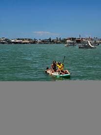A group enjoys paddleboarding on a sunny day, showcasing fun water activities and camaraderie in a vibrant setting.