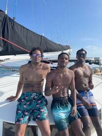 Three friends enjoy a sunny day aboard a catamaran, showcasing a fun and relaxed atmosphere perfect for summer adventures on the water.