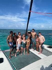 A joyful group of friends celebrates on the deck of a catamaran, enjoying the sun and water — perfect for memorable outings and adventures on the sea.