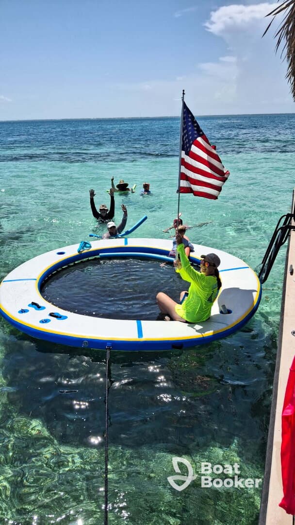 A lively group enjoys a fun day on the water, featuring a floating mat and snorkeling gear, perfect for family adventures in crystal-clear waters.