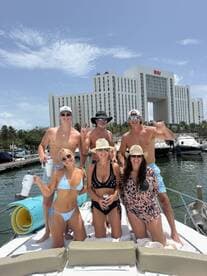 A lively group of friends enjoys a fun day on the boat, celebrating with drinks and smiles against a vibrant marina backdrop.