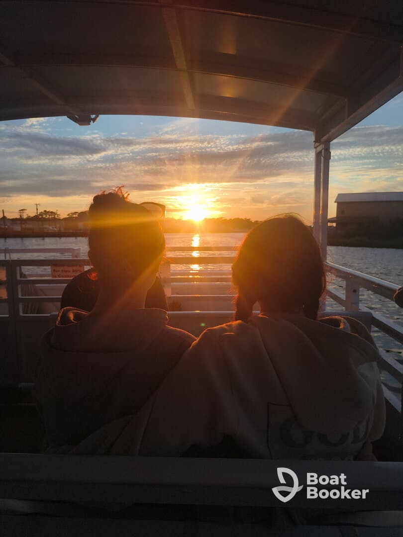 Two friends enjoy a stunning sunset view from the deck of a boat, creating a perfect backdrop for memorable moments on the water.