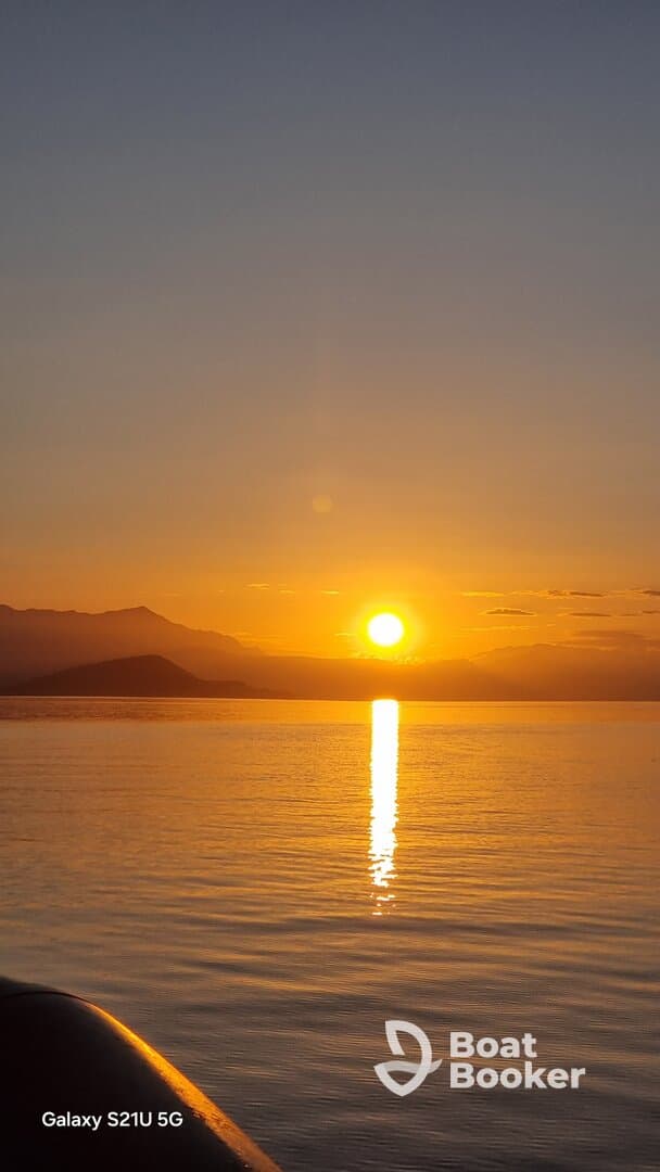 A stunning sunset over calm waters, with the silhouette of a boat in the foreground — perfect for capturing the serene beauty of evening cruises.