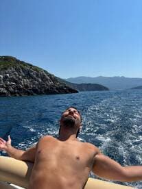 A man enjoys the sun and sea breeze while relaxing on a boat, capturing the essence of a perfect day on the water.