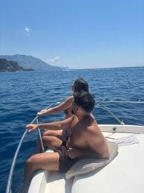 A couple enjoys a scenic view from the bow of a boat, soaking in the sun and ocean breeze — perfect for romantic getaways or adventurous outings on the water.