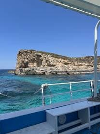 A stunning view of a rocky coastline from aboard a boat, showcasing the vibrant turquoise waters and clear blue skies — perfect for a day of exploration and adventure.