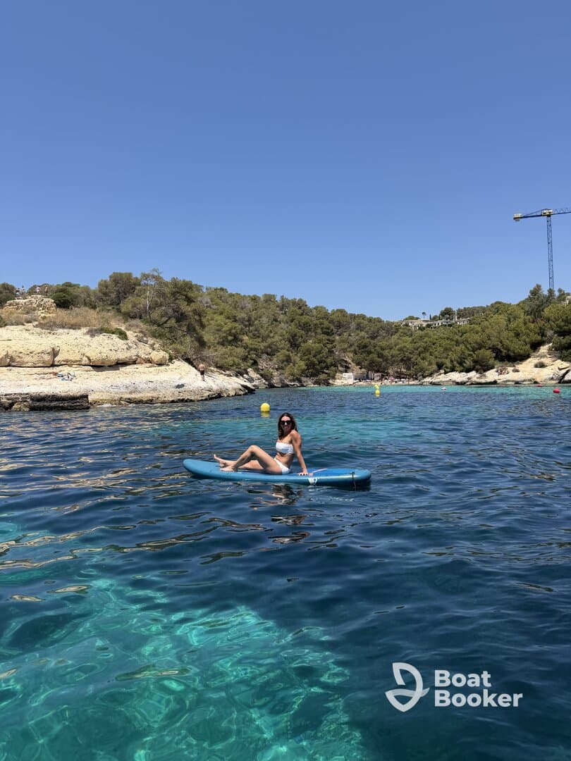 A woman enjoys paddleboarding in crystal-clear waters, surrounded by stunning natural scenery — a perfect summer activity for adventure seekers.