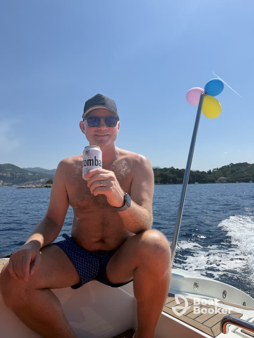 A man enjoys a refreshing drink while relaxing on a boat under the sun, capturing the essence of a perfect day on the water.