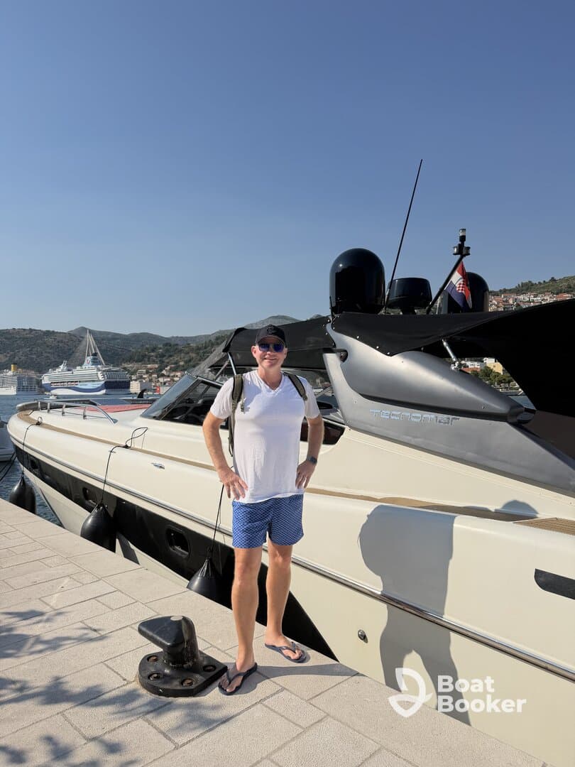 A man stands proudly next to a sleek boat at the dock, capturing the essence of a perfect day on the water.