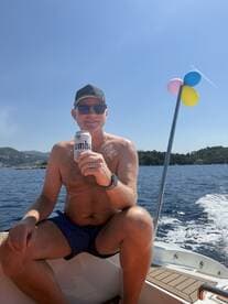 A man enjoys a refreshing drink while relaxing on a boat under the sun, capturing the essence of a perfect day on the water.