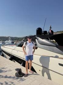 A man stands proudly next to a sleek boat at the dock, capturing the essence of a perfect day on the water.