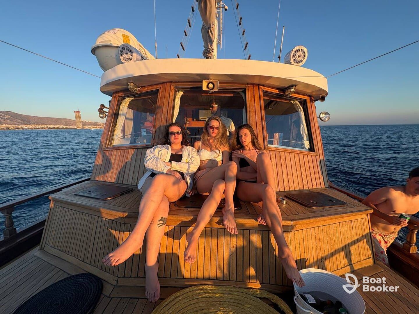 A group of friends relaxes on the deck of a boat during sunset, enjoying the beautiful ocean views — perfect for memorable summer outings.